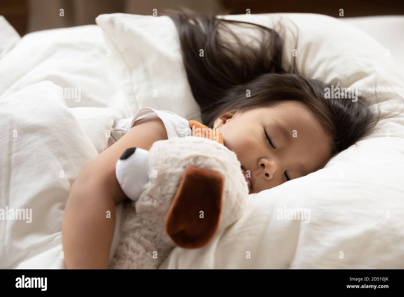 Cerrar lindo y sereno niña asiática abrazando juguete, durmiendo Foto de stock