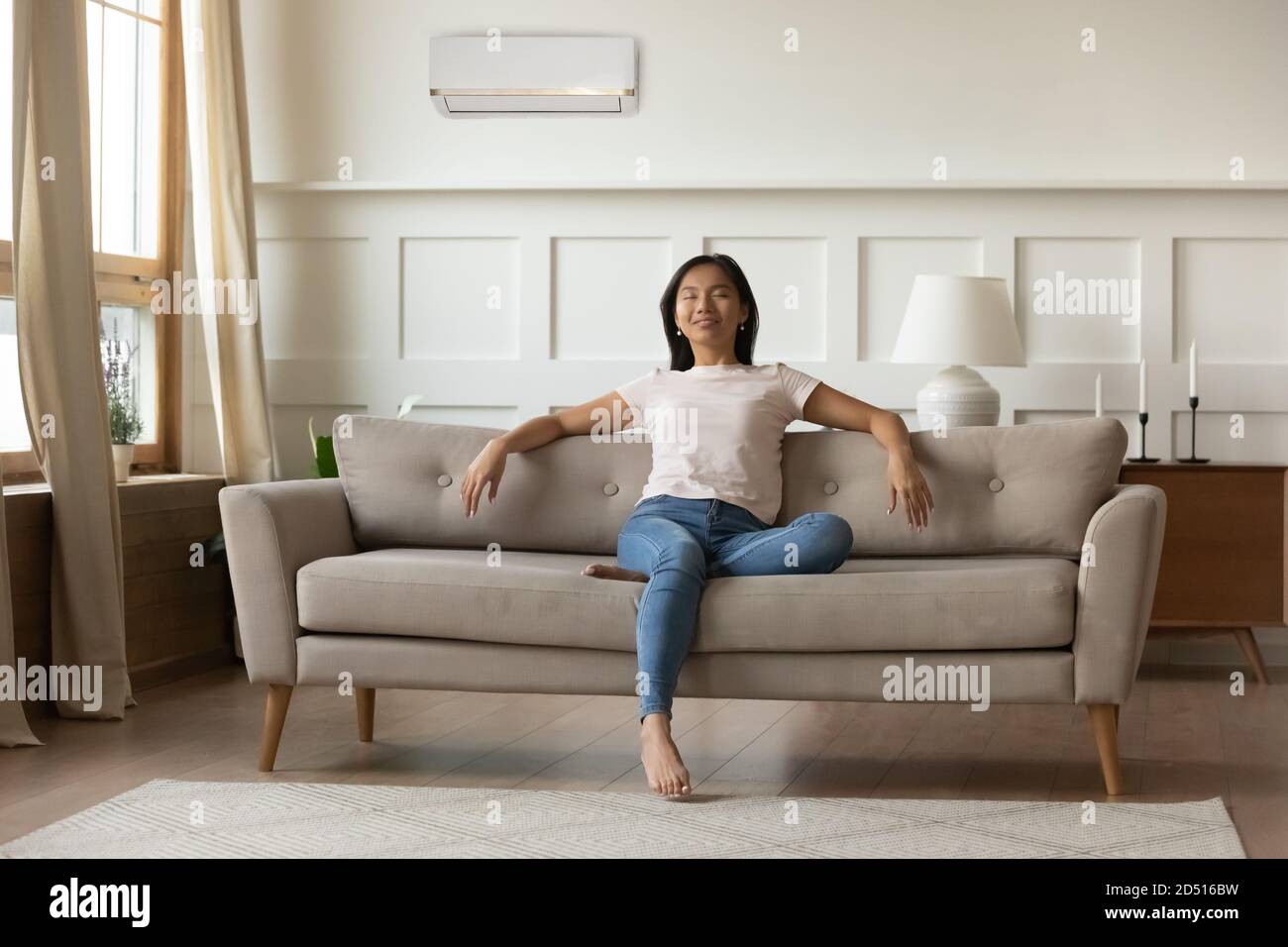 Tranquila mujer asiática joven relajante en la habitación con aire acondicionado Foto de stock