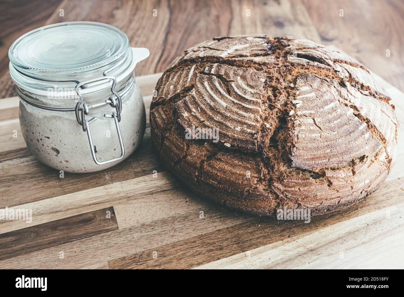 pan casero recién horneado de masa fermentada de centeno y entrante de masa fermentada tarro sobre mesa de madera Foto de stock