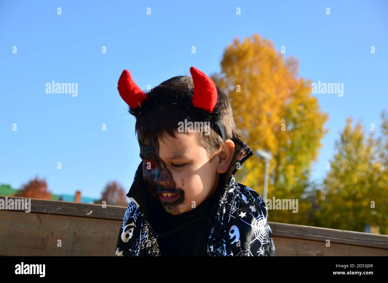 divertido bebé en el diablo disfraz de halloween con cuernos y tridente en  un chico de madera oscura con maquillaje negro para halloween, zombi  Fotografía de stock - Alamy