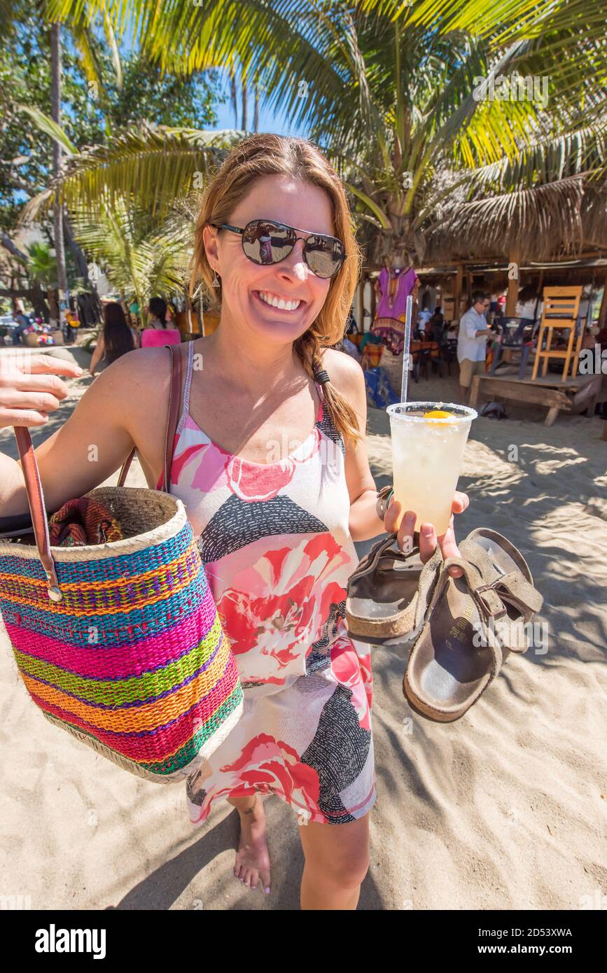 Hermosa mujer con ropa colorida sosteniendo un cóctel fresco caminando por  la playa. San Pancho, San Francisco, Nayarit, México Fotografía de stock -  Alamy