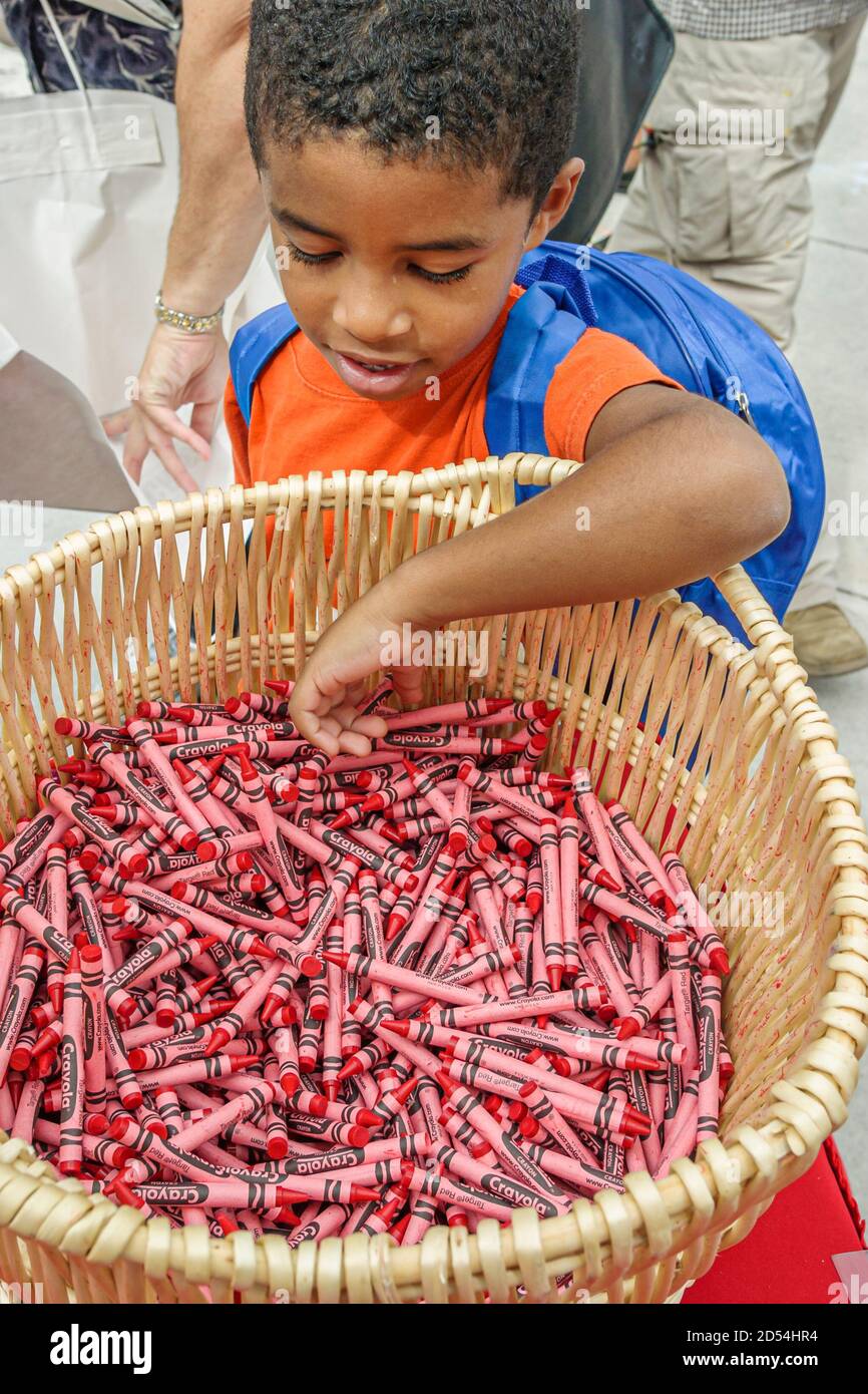 Miami Florida,Dade College campus,International Book Fair vendor stall seller books,Black African boy basket crayons red, Foto de stock