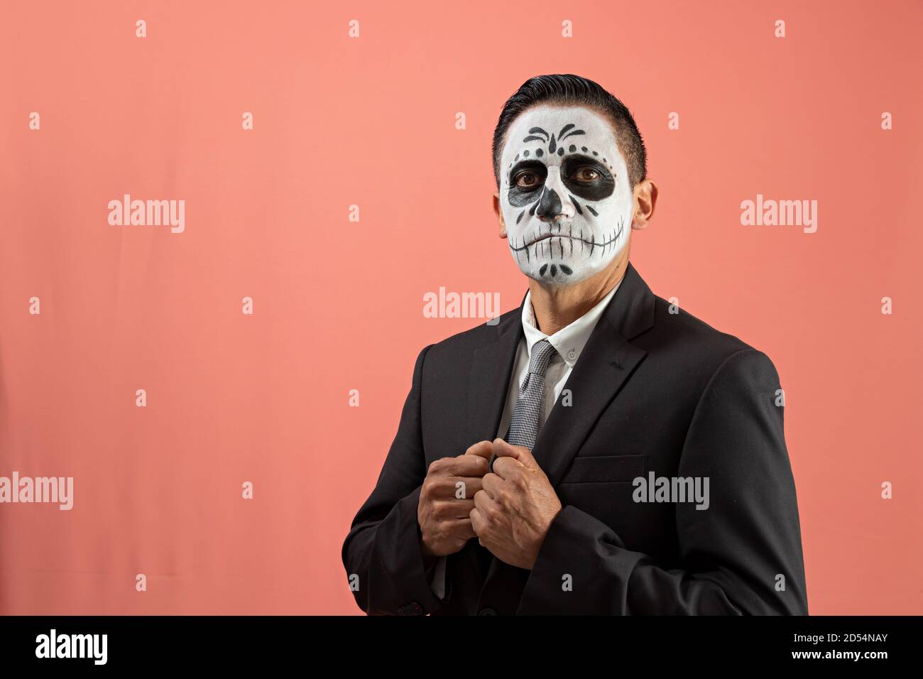 Hombre disfrazado de catrin con traje negro y corbata gris, posando con  fondo liso Fotografía de stock - Alamy