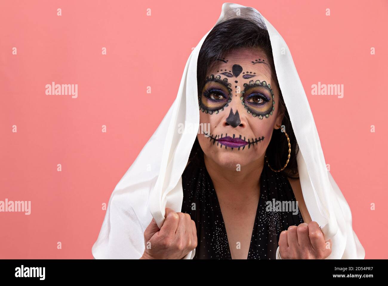 mujer disfrazada como una catrina, vestida con un vestido negro y un  chaparrón blanco posando con un fondo liso Fotografía de stock - Alamy