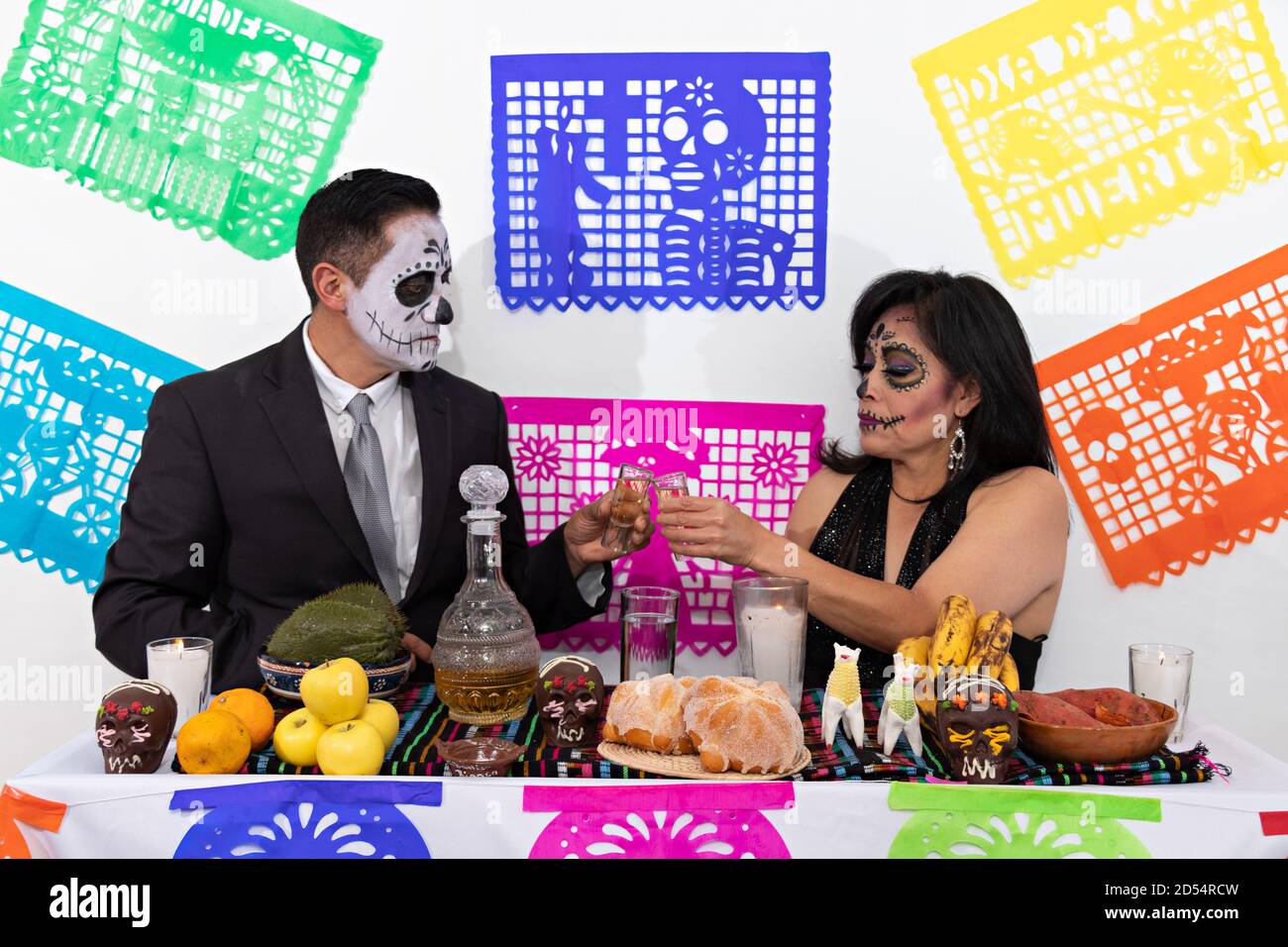 Catrin y Catrina maquillaje pareja toasting con un tiro de tequila detrás  de un tradicional altar mexicano en el día de los muertos Fotografía de  stock - Alamy