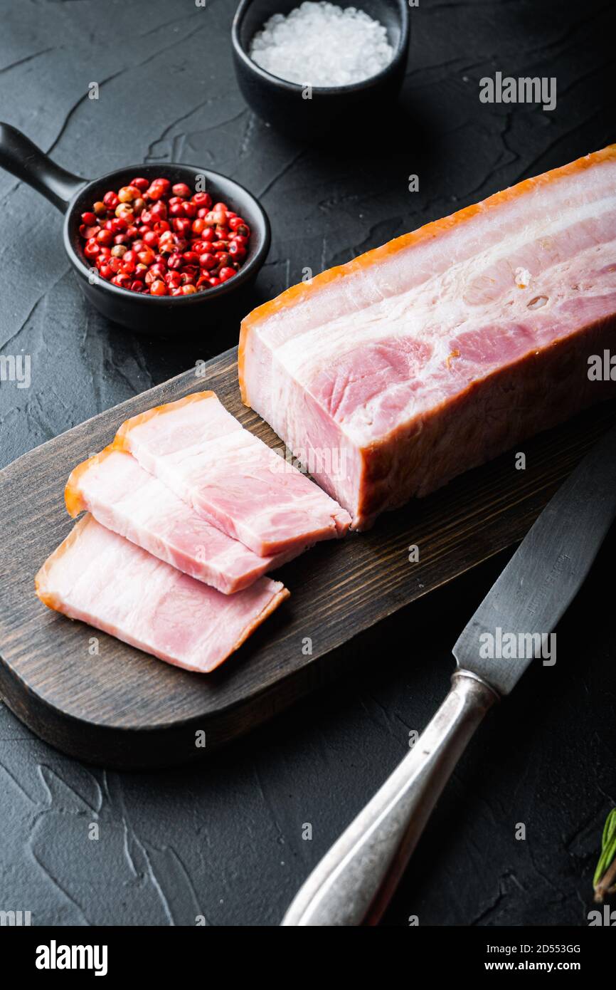 Panceta de tocino cortada y cortada en rodajas con hierbas sobre fondo negro Fotografía de stock