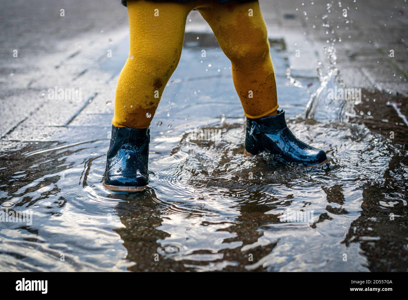 7 de octubre de 2020, Trebbin, una niña pequeña con zapatos de goma y  medias amarillas salta en un charco y tiene mucha diversión. | uso en todo  el mundo Fotografía de stock - Alamy