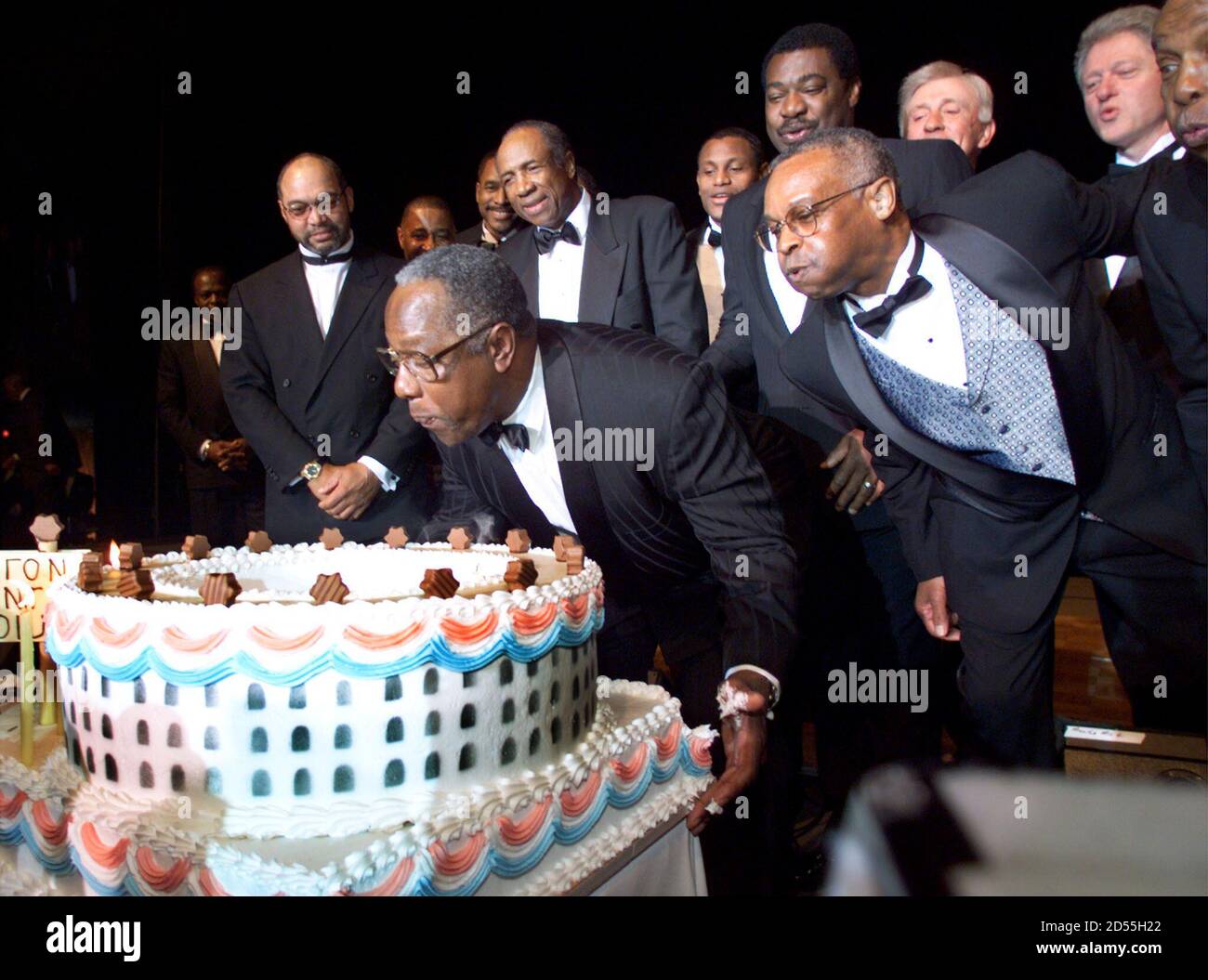 El presidente Bill Clinton observa (arriba, derecha) como Hank Aaron sopla  velas de cumpleaños de su pastel de cumpleaños, con forma similar al  estadio del condado de Fulton de Atlanta 5 de