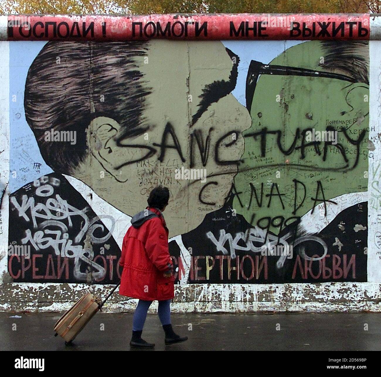 Una Mujer Mira El Graffiti El 2 De Noviembre Mostrando Al Ex Lider Sovietico Leonid Brezhnev L Besando A Su Homologo De Alemania Oriental Erich Honecker R Pintado En Un Segmento Del