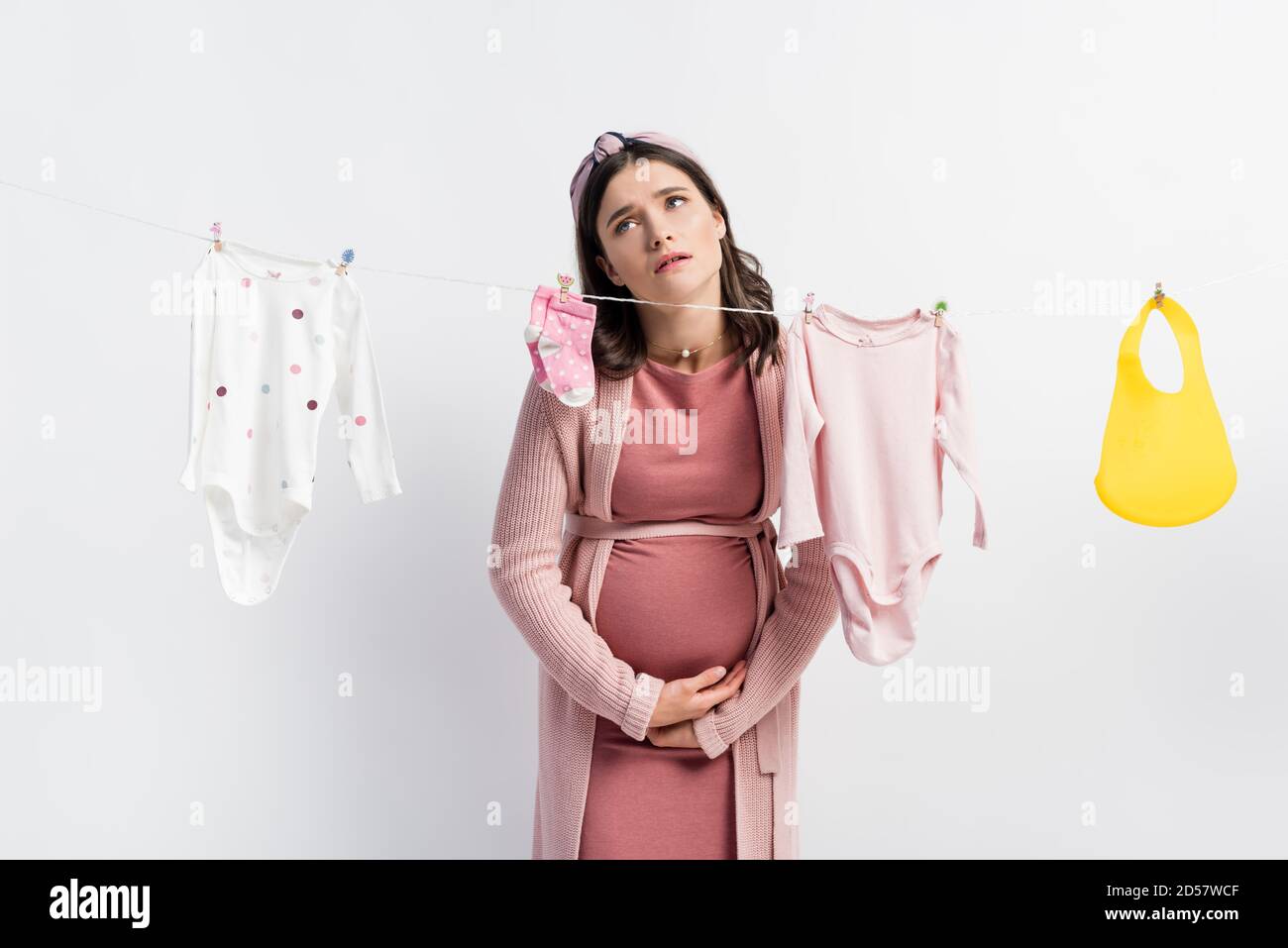 Mujer Embarazada Triste Tocando El Vientre Cerca De La Ropa Del Bebe En La Ropa Linea Aislada Sobre Blanco Fotografia De Stock Alamy