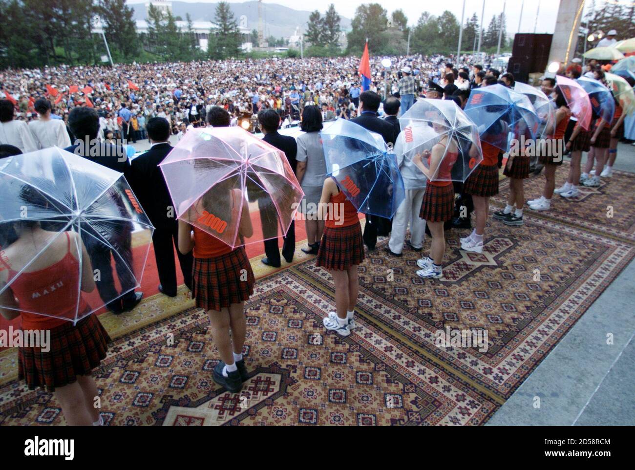 Las en minifaldas forman una línea de paraguas mientras se encuentran detrás de los políticos locales durante la última campaña organizada por el Partido Revolucionario del Pueblo de (