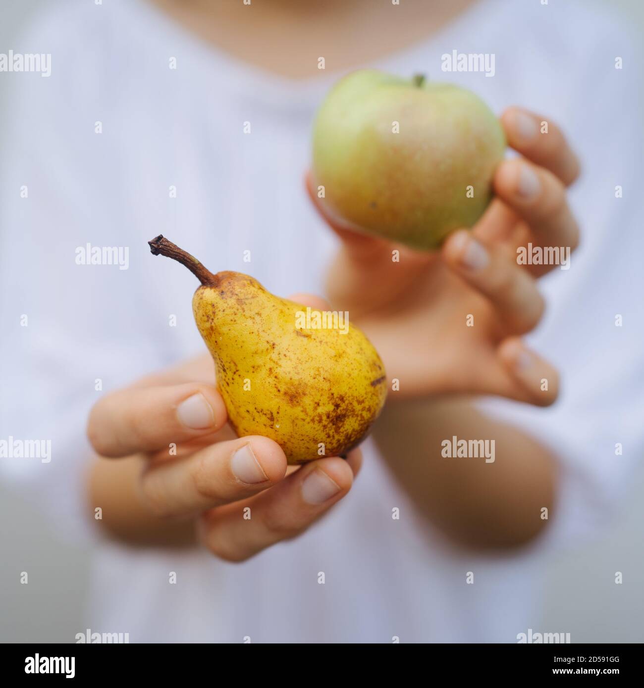 Primer plano de una mujer sosteniendo una manzana y una pera Foto de stock