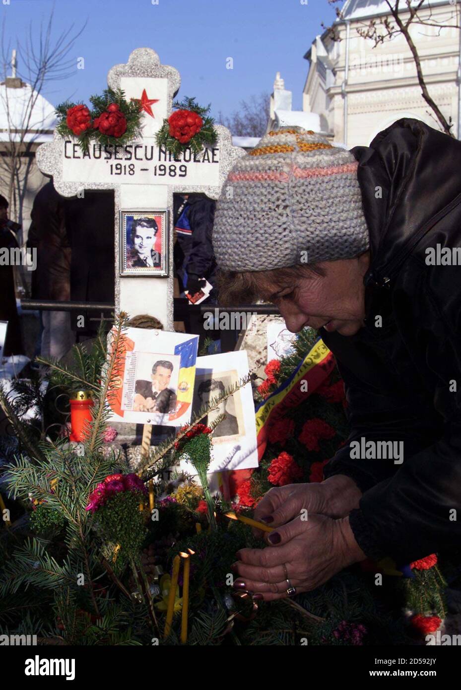 A woman lights a candle at the grave of Romania's late dictator Nicolae