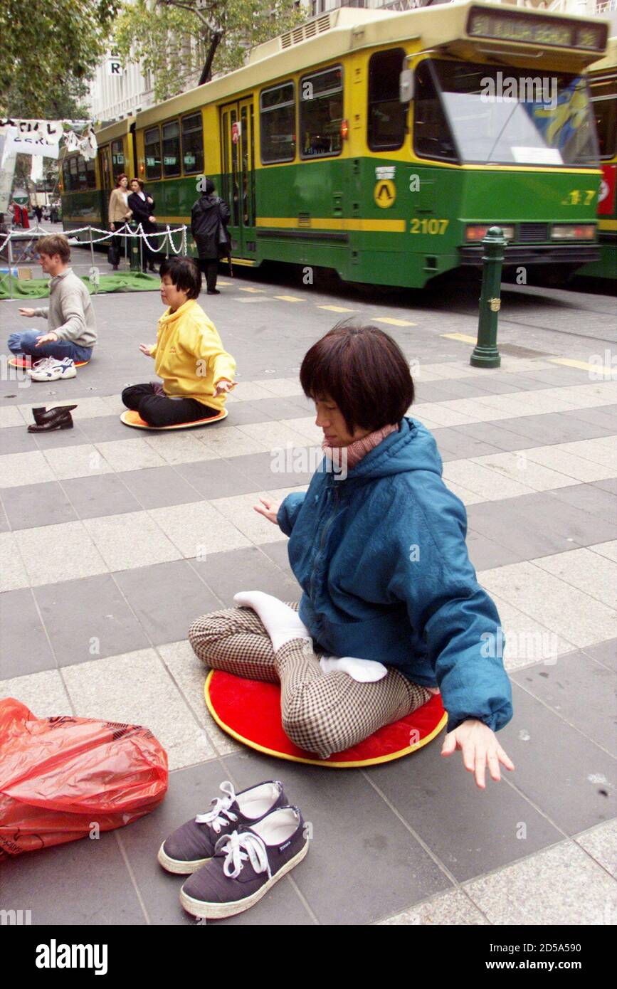 Los practicantes de Falun Gong con sede en Melbourne meditan en el centro de Melbourne mientras un tranvía pasa por el centro comercial de la calle Bourke 19 de agosto. Los miembros del grupo de artes marciales pasivas estaban ofreciendo clases introductorias afirmando que millones de personas en todo el mundo se habían beneficiado de los ejercicios que dicen que son buenos para la auto-curación, el alivio del estrés y la mejora de la salud. Recientemente en Beijing, las autoridades reprimieron y prohibieron el movimiento. ??» Foto de stock