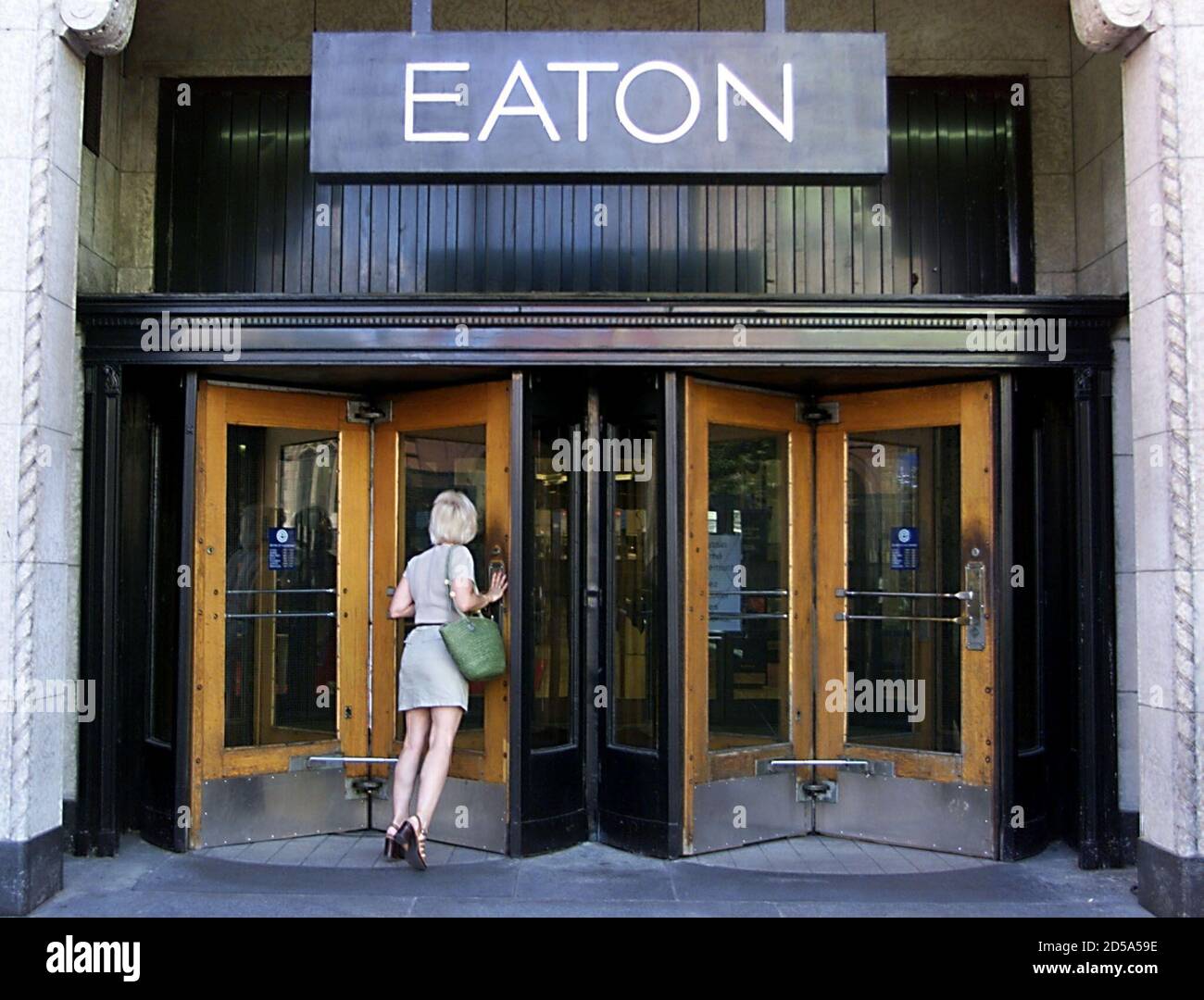 Un comprador empuja contra una puerta cerrada en la tienda insignia cerrada  de Eaton en el centro de Montreal, agosto de 20. Al borde del colapso, la  cadena de tiendas por departamentos