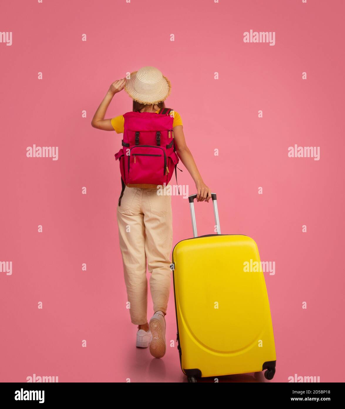 Vista posterior de mujer mochilero con maleta sobre fondo rosa Fotografía  de stock - Alamy