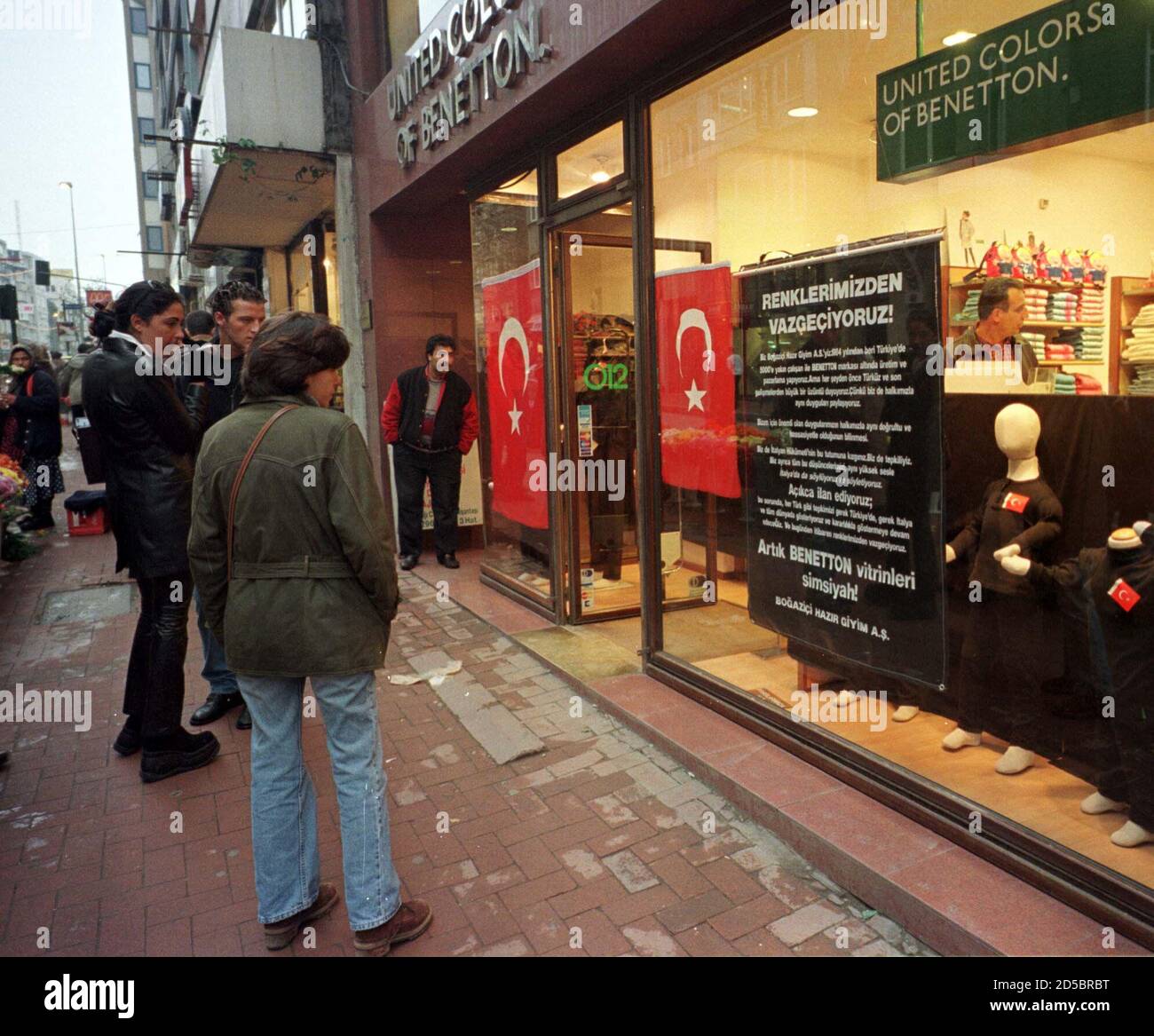 Los compradores turcos leen un anuncio en la ventana de la tienda de ropa  italiana Benetton que colgaba cortinas negras para expresar su protesta  ante el gobierno italiano el 21 de noviembre