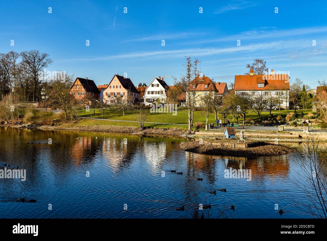 Dinkelsbühl en el momento del bautismo. Casa de entramado de madera de colores, casas, lago, cielo azul. Baden-Wurttemberg, Alemania. Foto de stock
