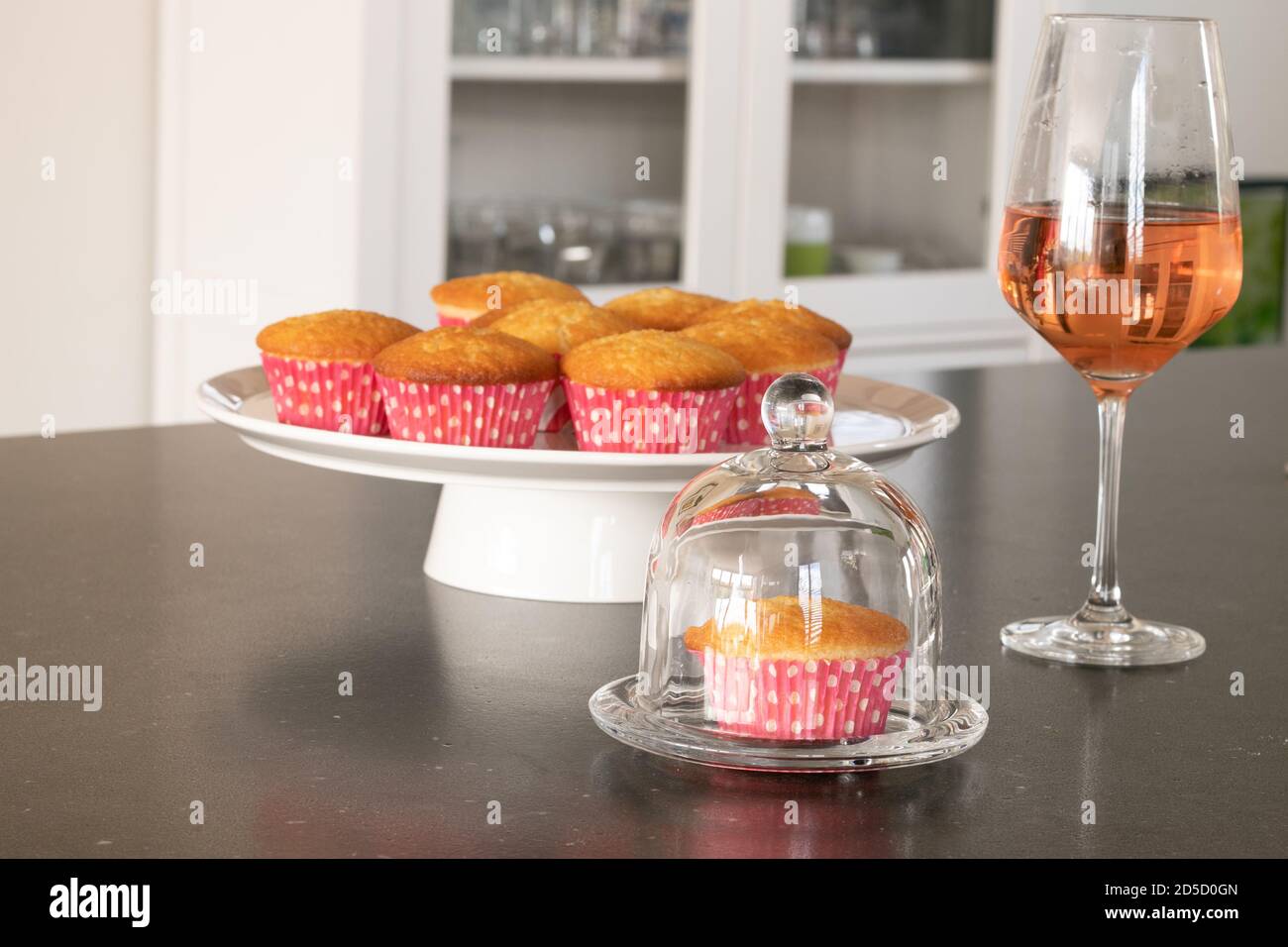 Cupcakes caseros horneados en un plato blanco o cristal y en un fondo oscuro de mesa, tazas rosadas con puntos de color blanco, cupcakes simples sin decoración. Inicio Foto de stock