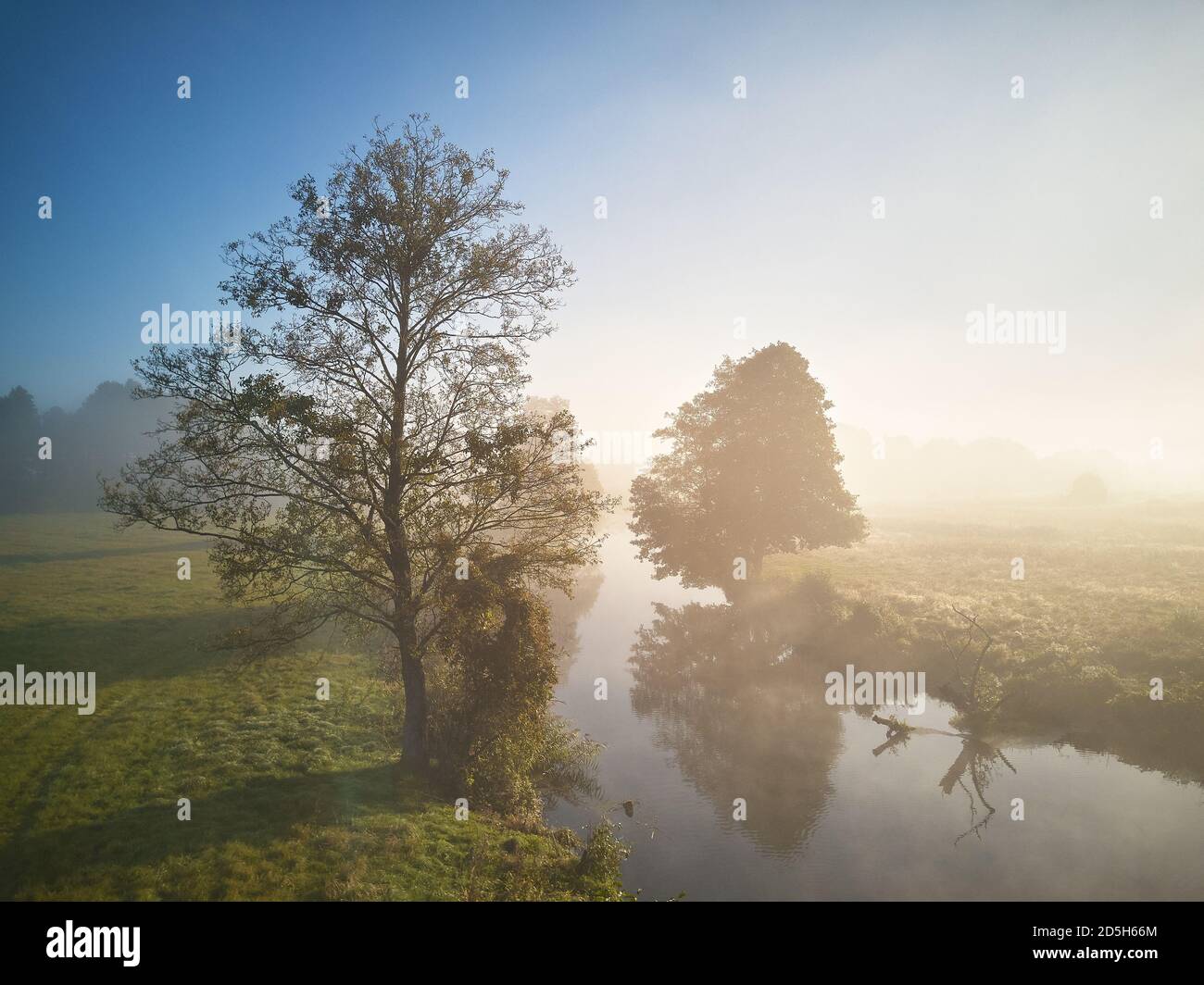 El amanecer de otoño es niebla. Colorido amanecer de mañana brumoso. Caída de la escena rural. Pequeño río con árboles en el prado y campo, Bielorrusia Foto de stock