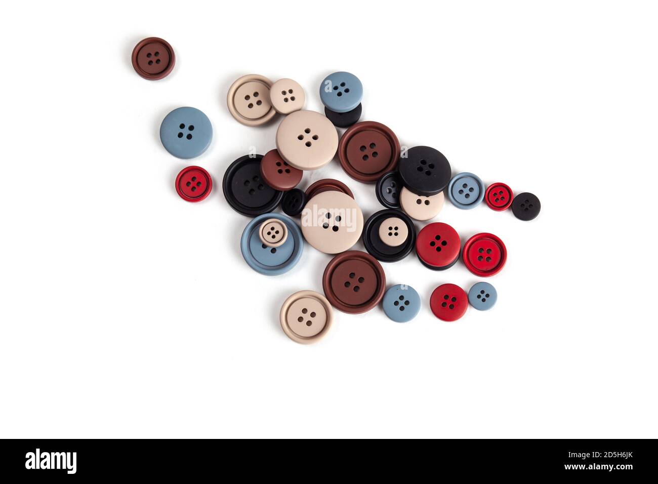 Pila de botones de color marrón, beige, gris, rojo, negro de plástico mate sobre blanco, hermosas agujas, minimalismo. Uso para coser. Espacio para texto. Foto de stock