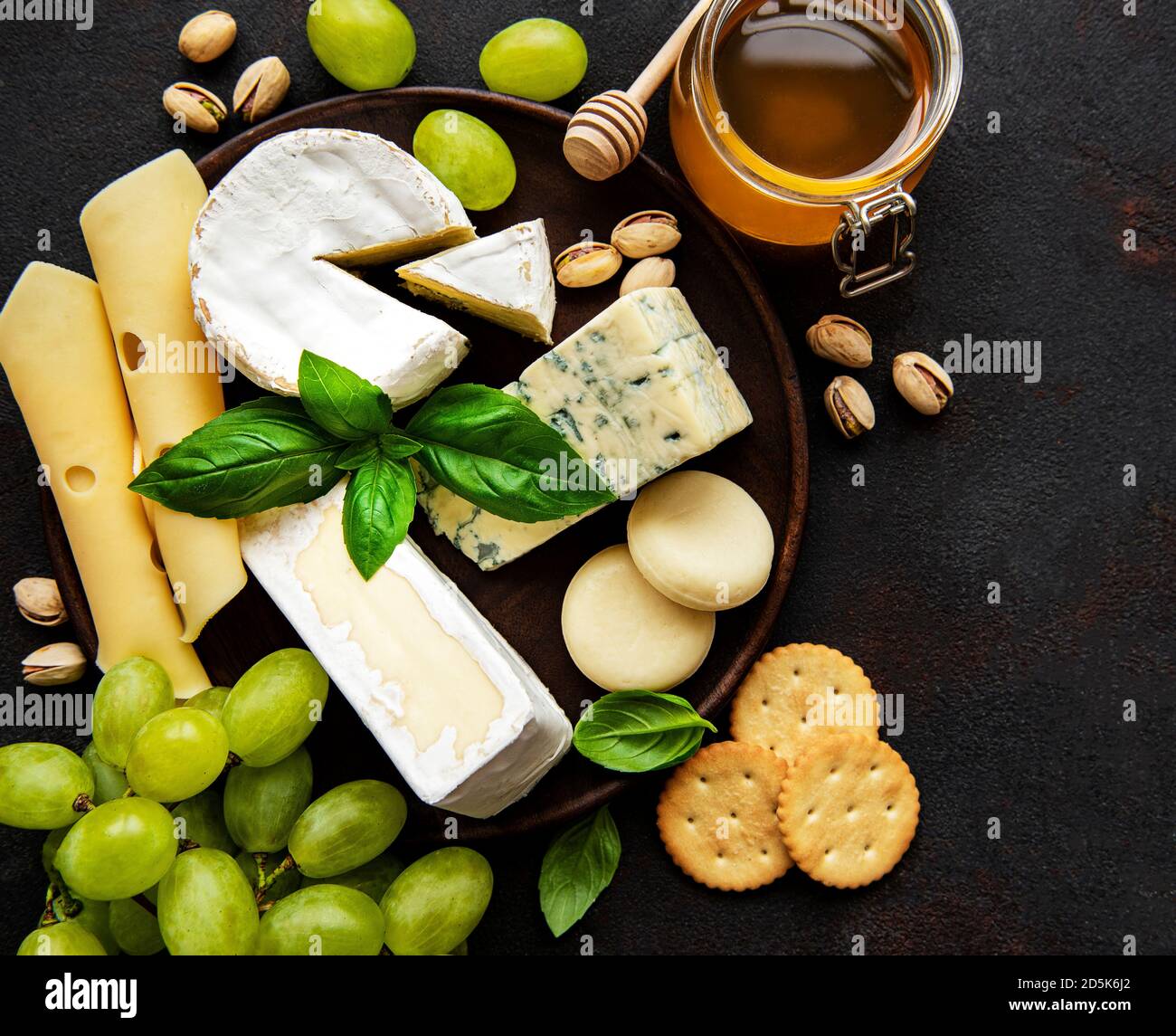 Varios tipos de queso sobre un fondo de concreto negro Foto de stock