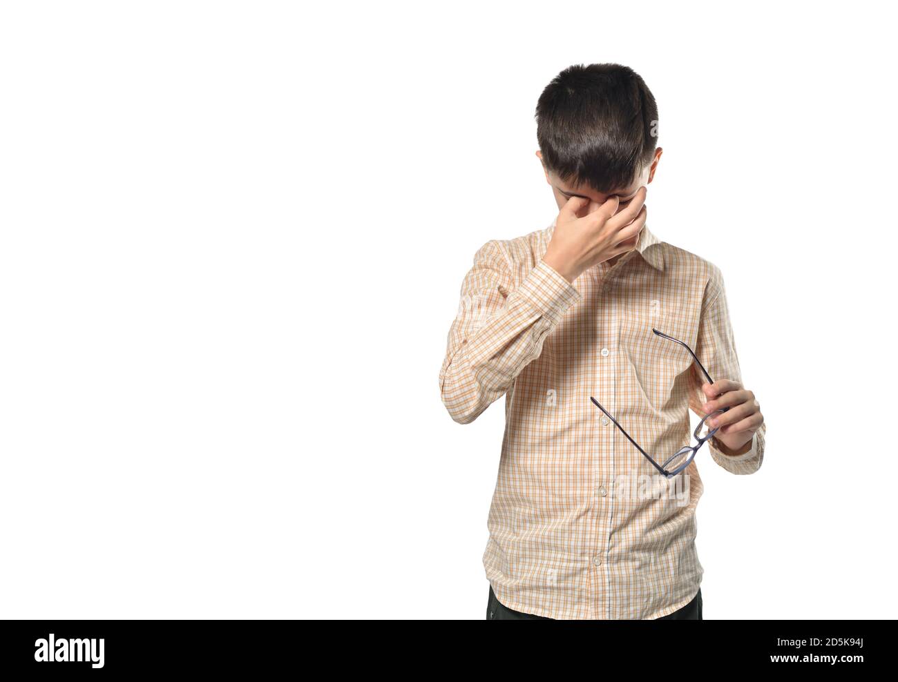 Niño de 13 años, se quitó las gafas y toca sus ojos cansados sobre un fondo blanco aislado Foto de stock