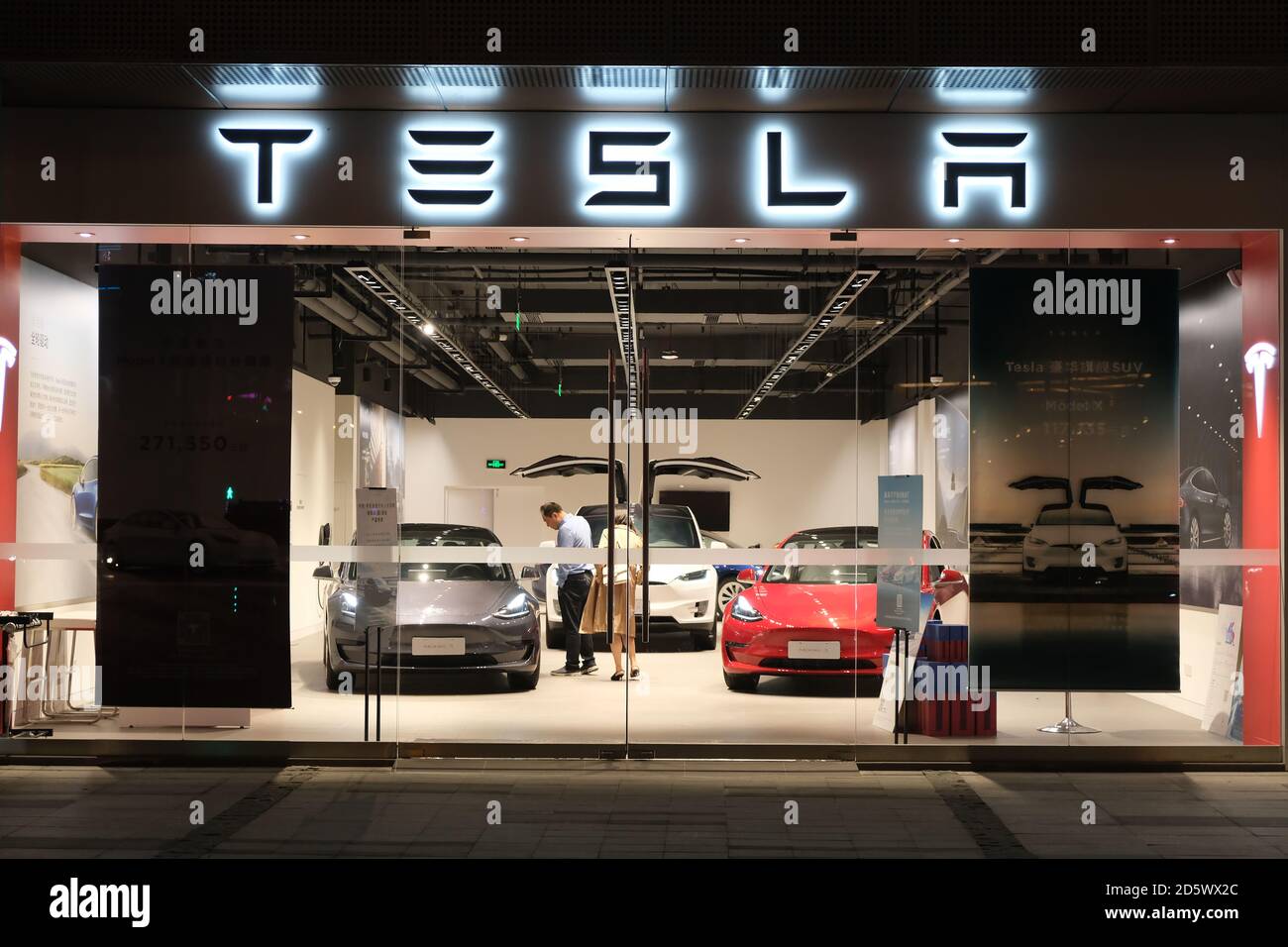 Fachada tienda Tesla por la noche. Clientes dentro de tienda Tesla elegir  coches eléctricos Fotografía de stock - Alamy