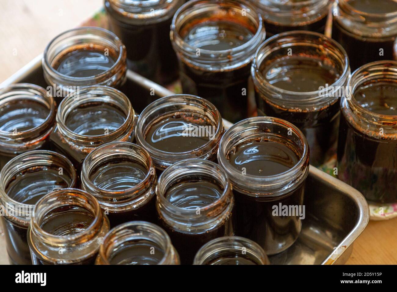 Jarras de mermelada con cubierta abierta llenas de membrillo líquido oscuro mermelada confitura casera conservar Foto de stock