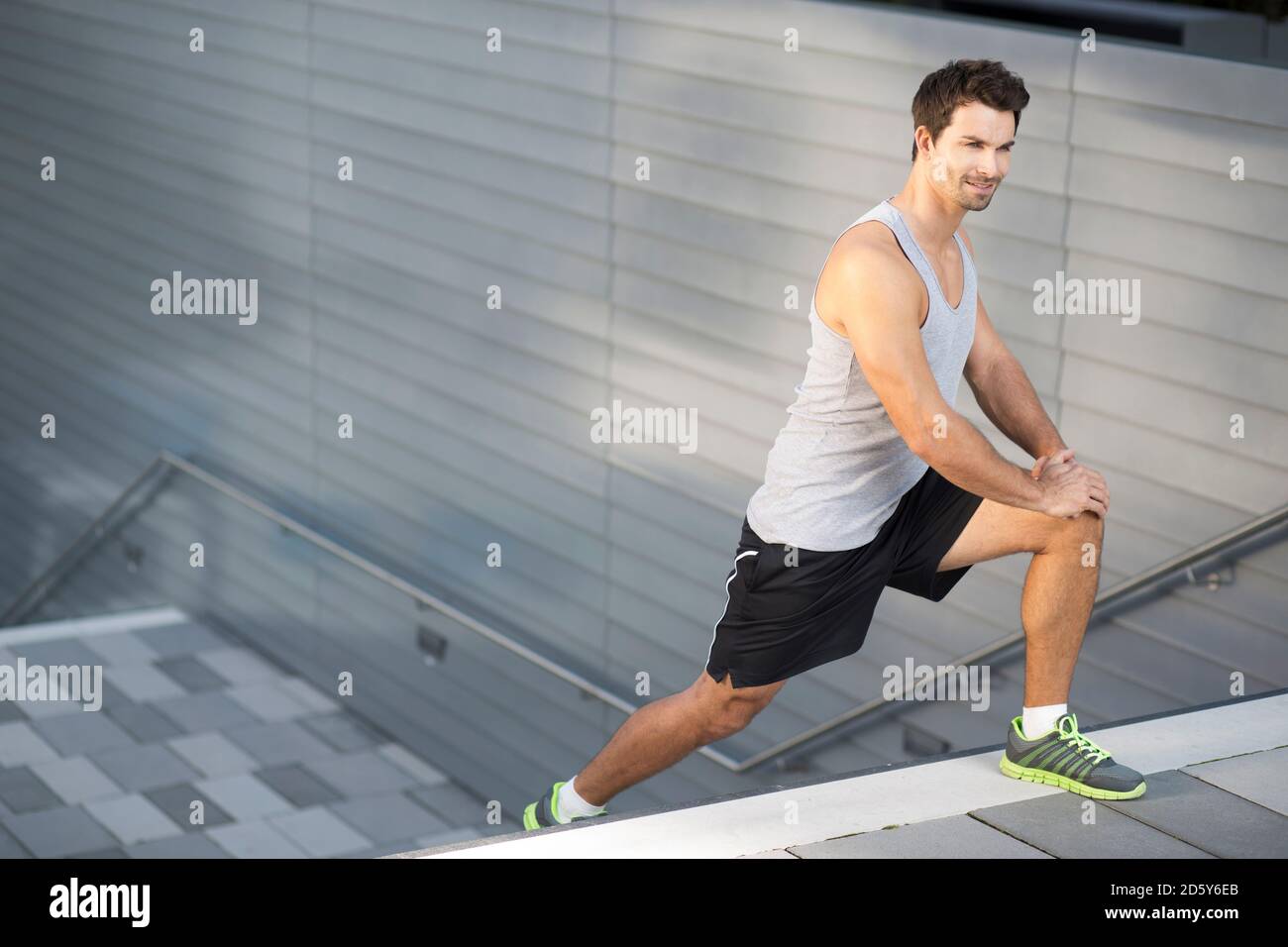 Deportista haciendo ejercicios de estiramiento en una escalera Foto de stock