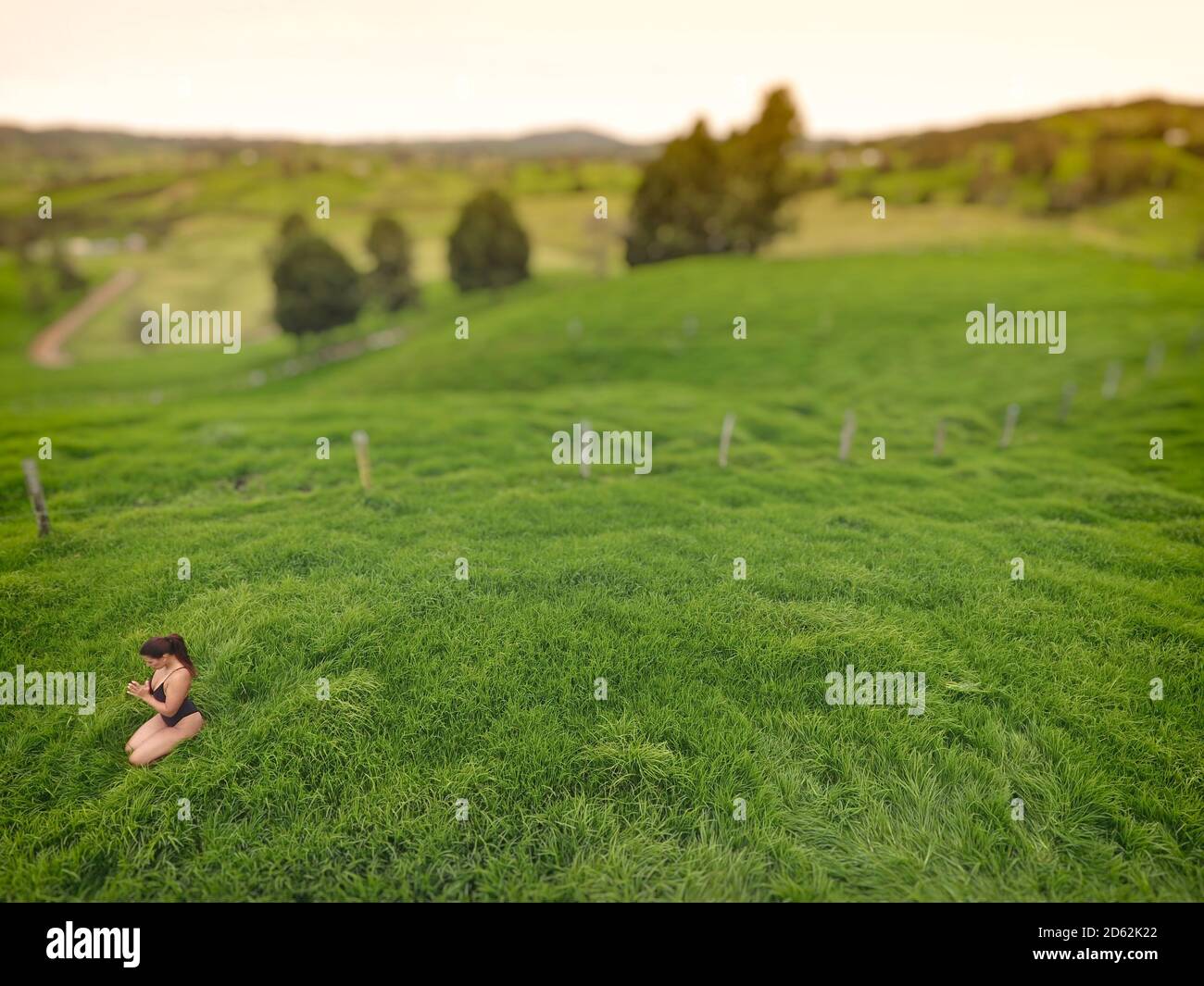 Mujer meditando en un campo de hierba vacío. Foto de stock