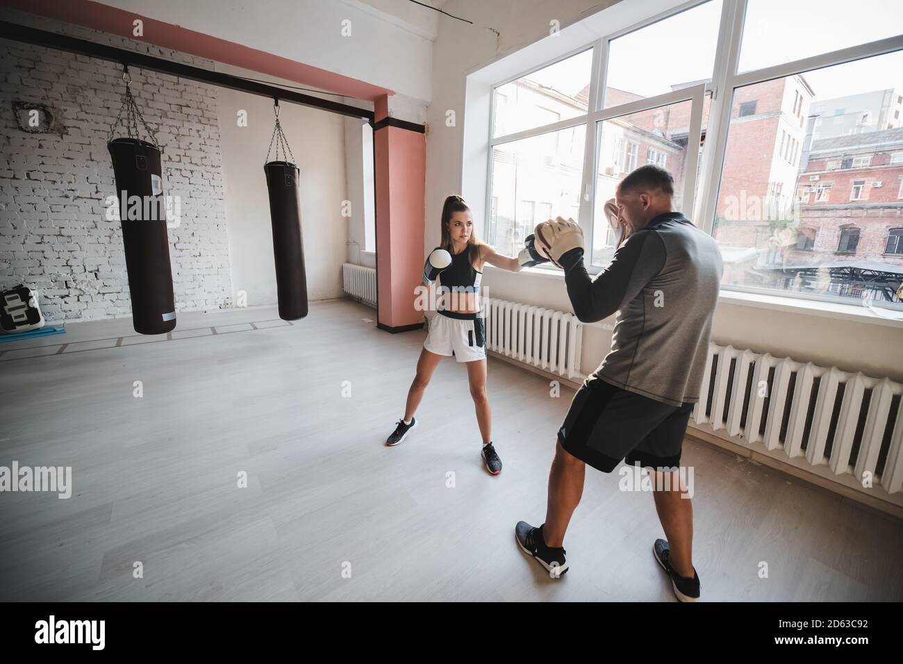 Un hombre y una mujer que escatiman compañeros se entrenan en el sala de entrenamiento de combatientes en guantes de boxeo con patas Foto de stock