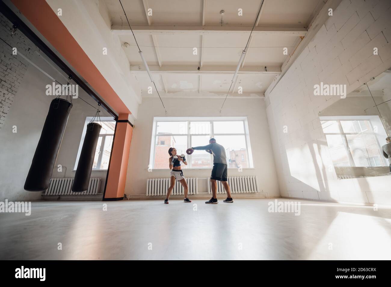 Un hombre y una mujer que escatiman compañeros se entrenan en el sala de entrenamiento de combatientes en guantes de boxeo con patas Foto de stock