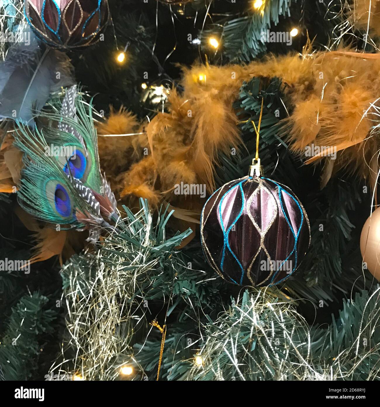 Decoración de Navidad en púrpura y oro con plumas de pavo real, luces y  bolas en un árbol de Navidad Fotografía de stock - Alamy