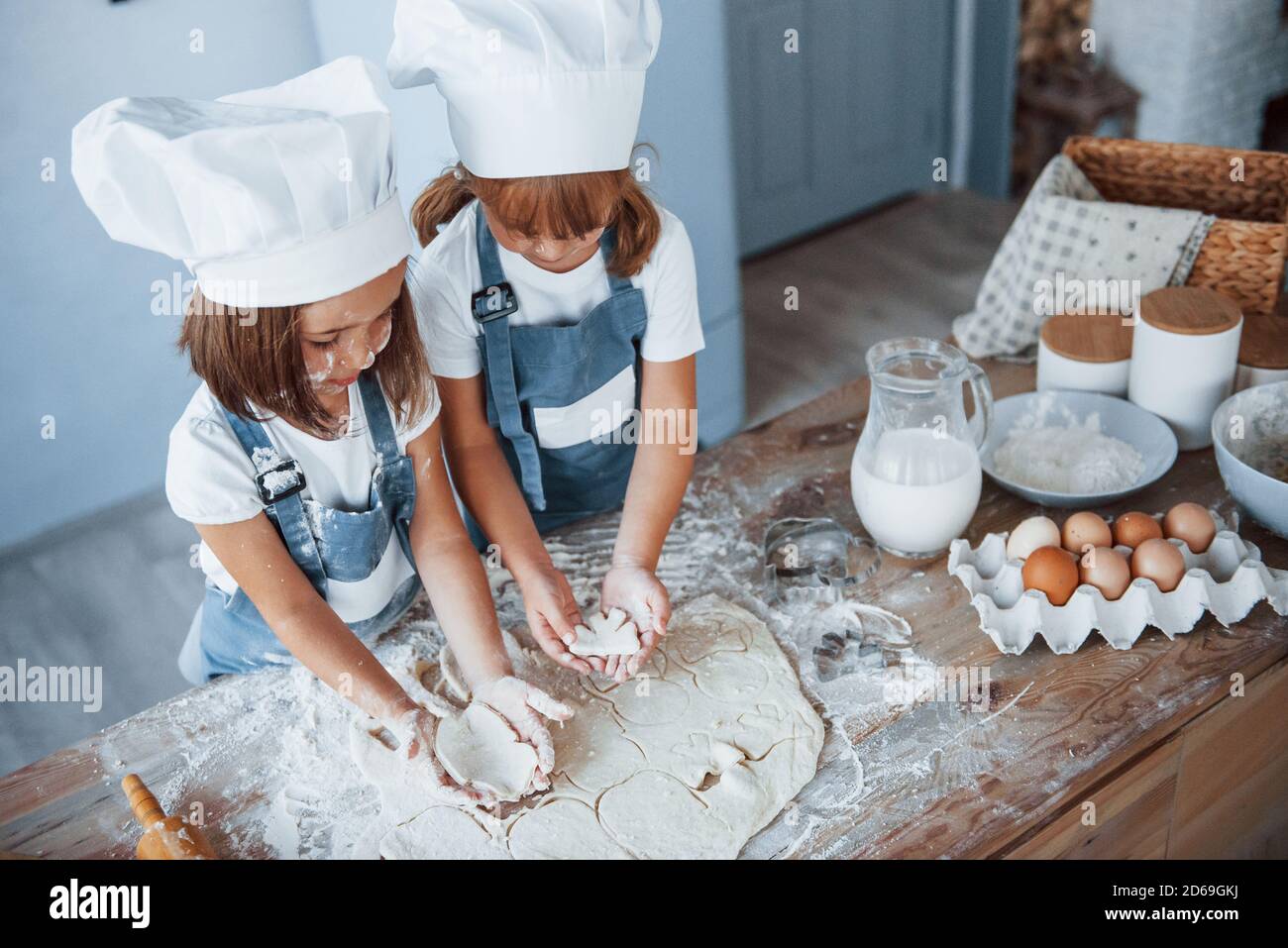 Concentrarse en cocinar. Los niños de la familia en el uniforme blanco del chef preparando la comida en la cocina Foto de stock