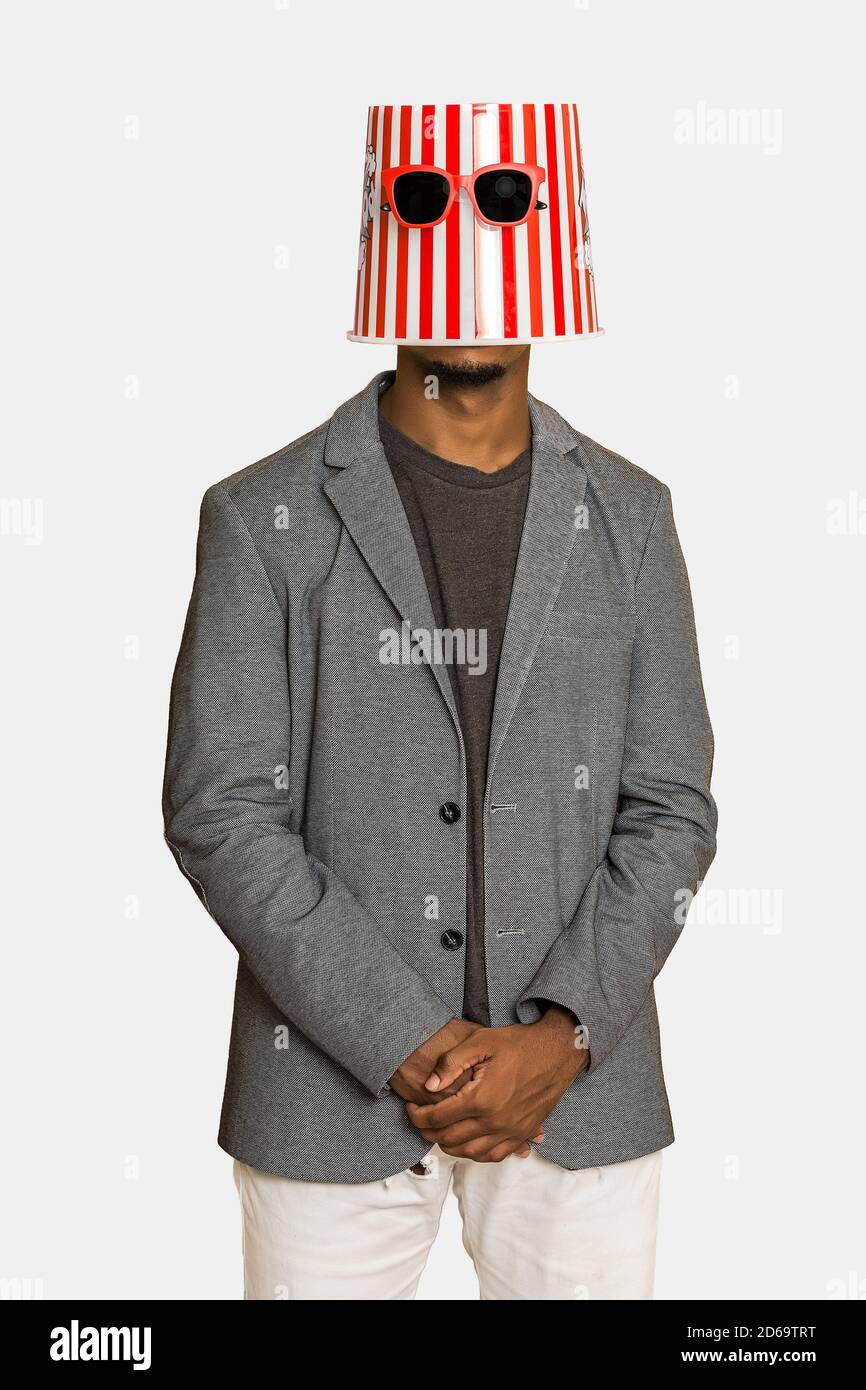 Hombre negro moderno en ropa informal elegante usando cubo de palomitas y  gafas de sol en la cabeza contra fondo gris Fotografía de stock - Alamy