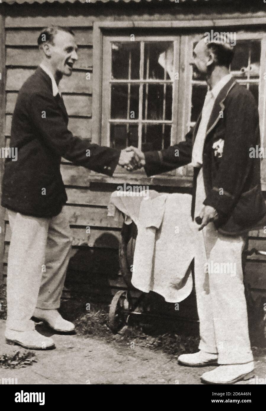 1925 - el jugador de críquet de Inglaterra y de Surrey británico Jack Hobbs, (Sir John Berry Hobbs 1882 – 1963, izquierda) recibiendo felicitaciones por anotar 126 siglos por su compañero de equipo W C H Sadler primera clase (William Cecil Holborn Sadler 1896-1981) Foto de stock