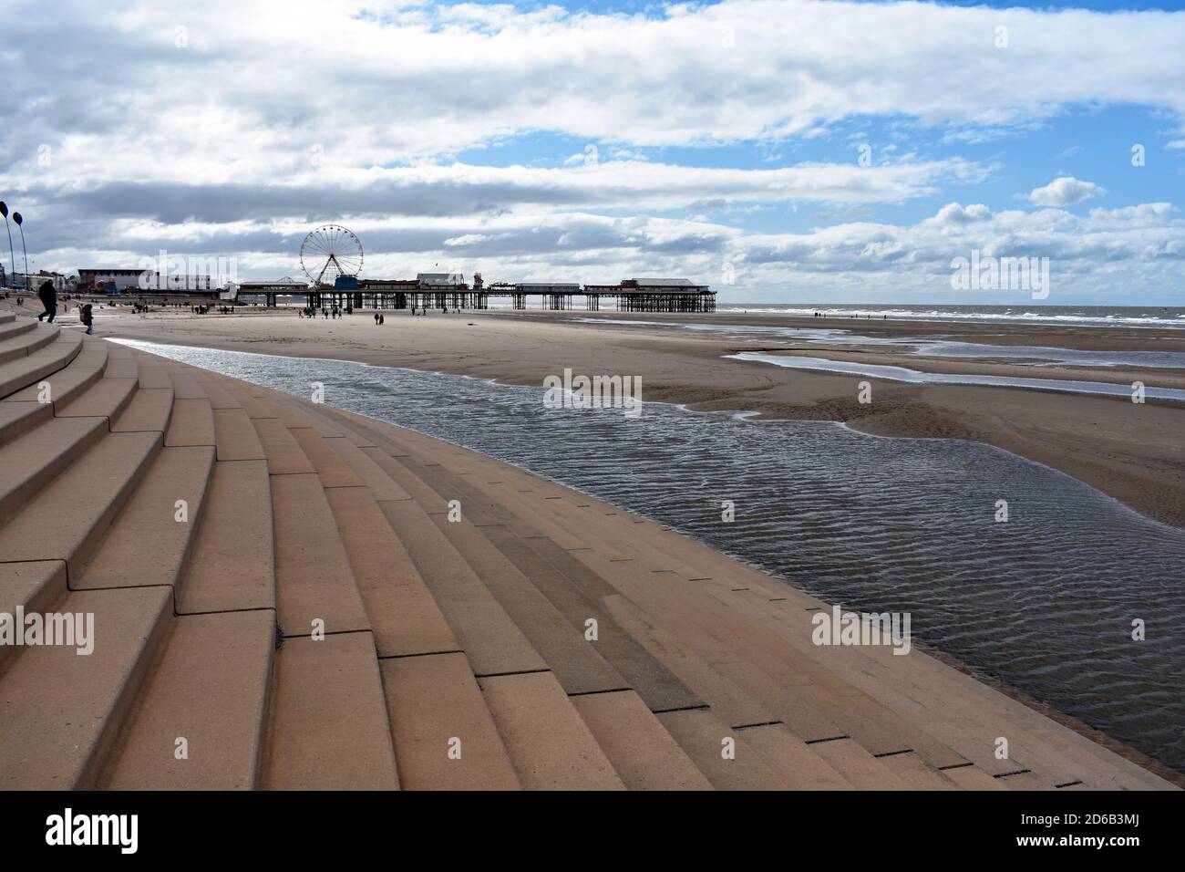 Los escalones conducen desde el paseo hasta la amplia playa de Blackpool, Lancashire, Inglaterra. El muelle central se puede ver que conduce al mar de Irlanda. Foto de stock