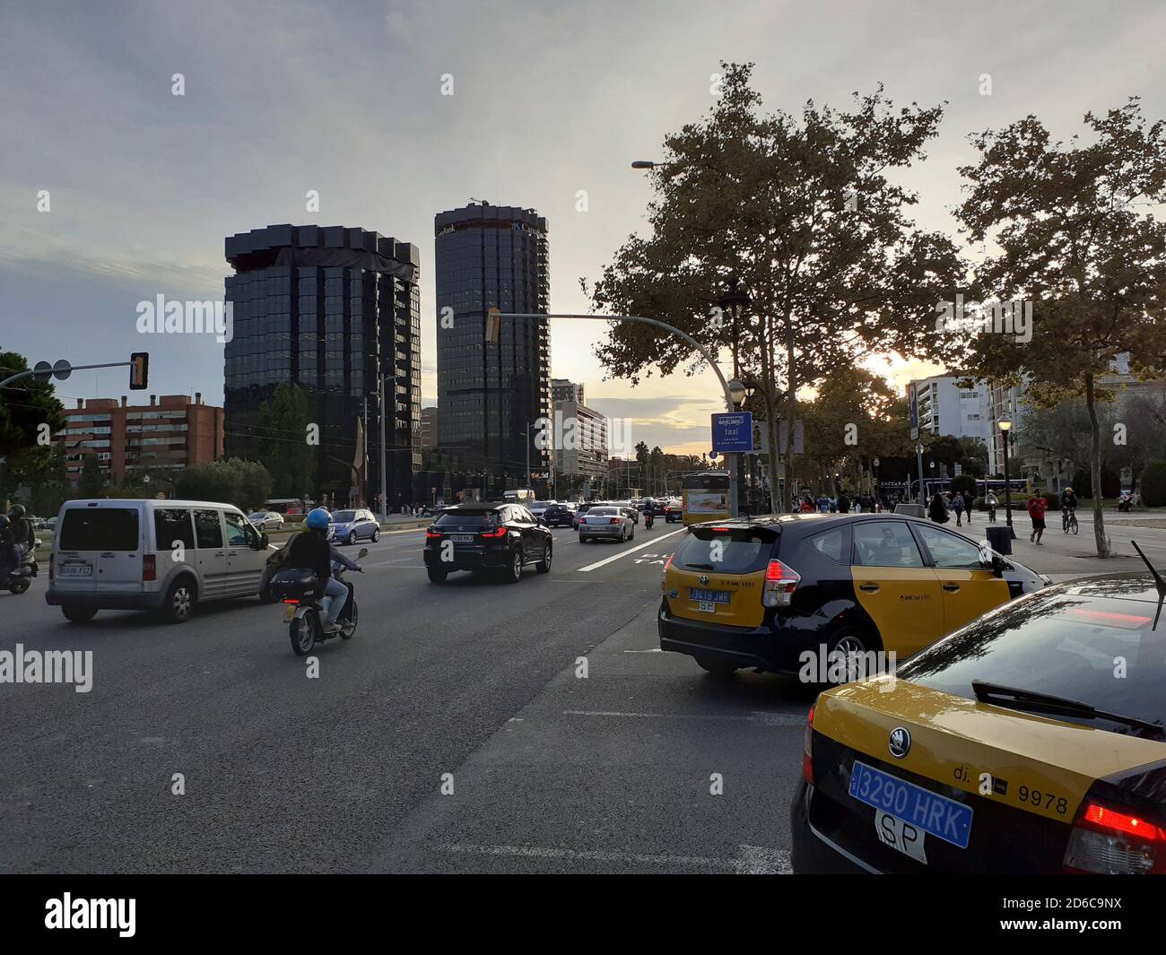 Avinguda Diagonal con el tráfico habitual los días laborables. En el fondo se encuentran los edificios históricos de Caixa Bank, el banco más poderoso de España. Foto de stock