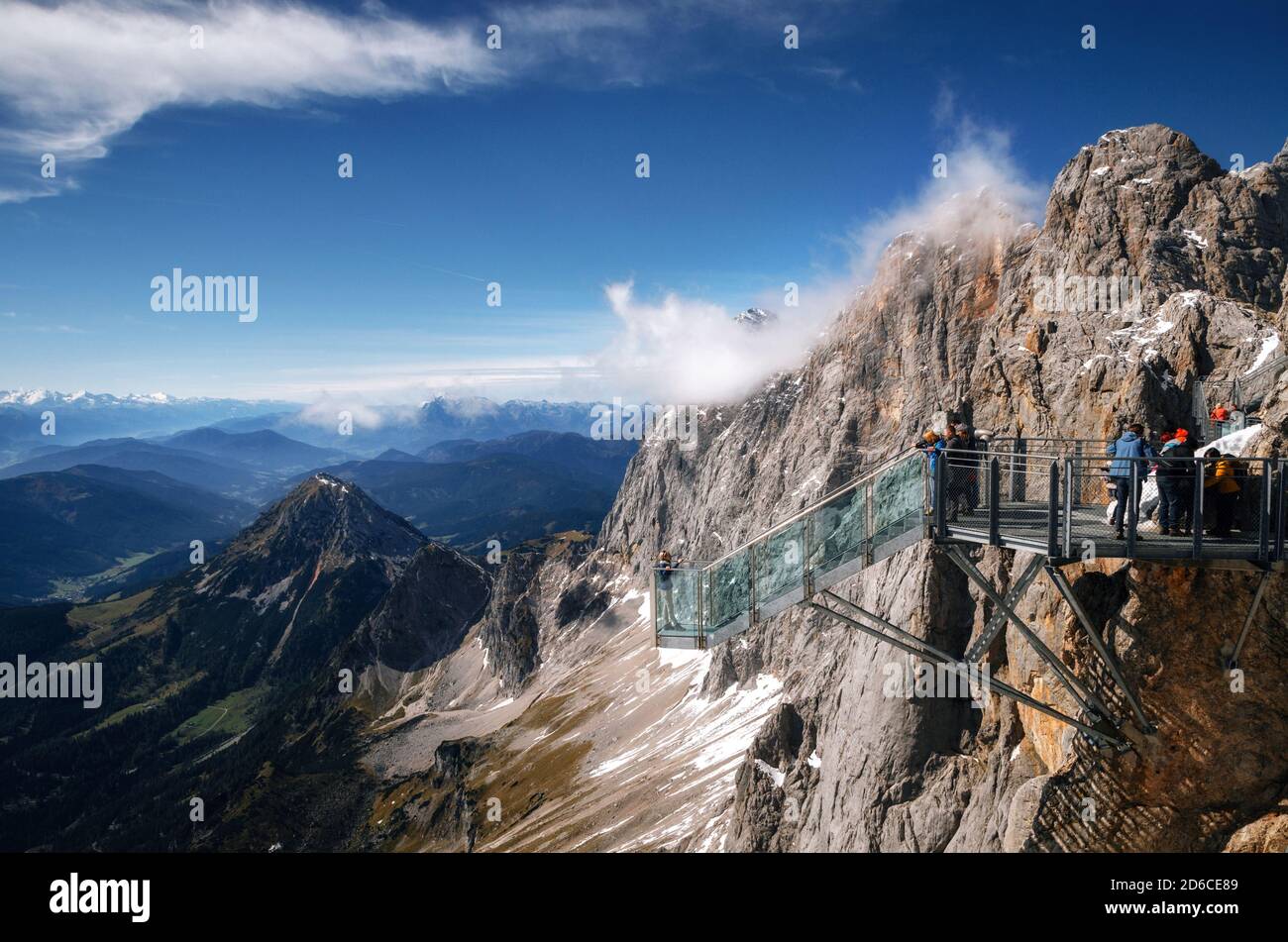 Los turistas se encuentran en la plataforma de observación del puente colgante Dachstein Montañas y goza del paisaje en Austria Foto de stock