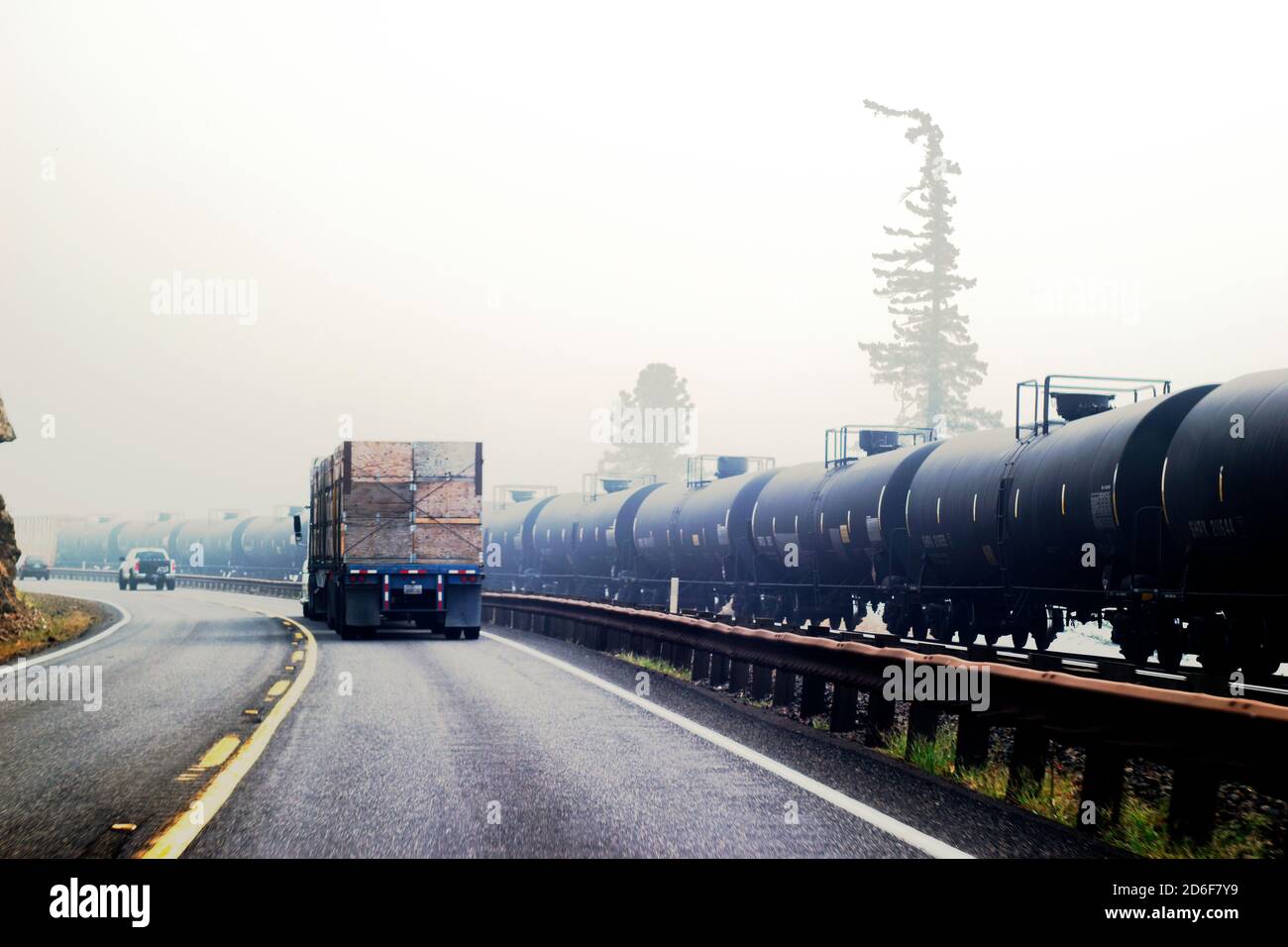 Humo de fuego salvaje y tráfico de la carretera junto al transporte de coches de ferrocarril aceite Foto de stock