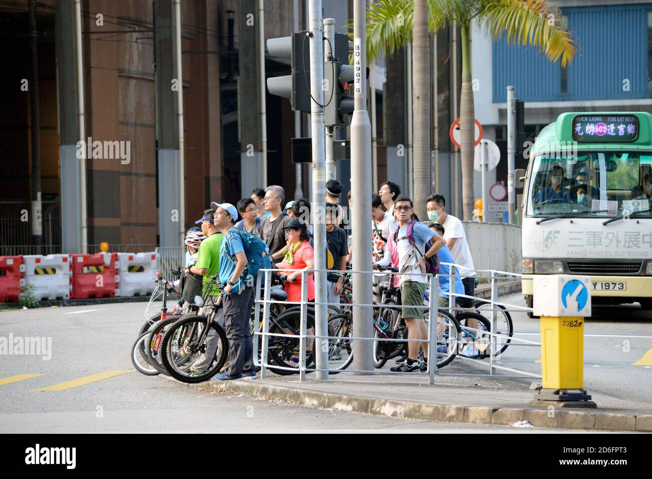 Muchos ciclistas se llenaron en una isla de refugio peatonal en un cruce escalonado en Yuen Long, Hong Kong Foto de stock