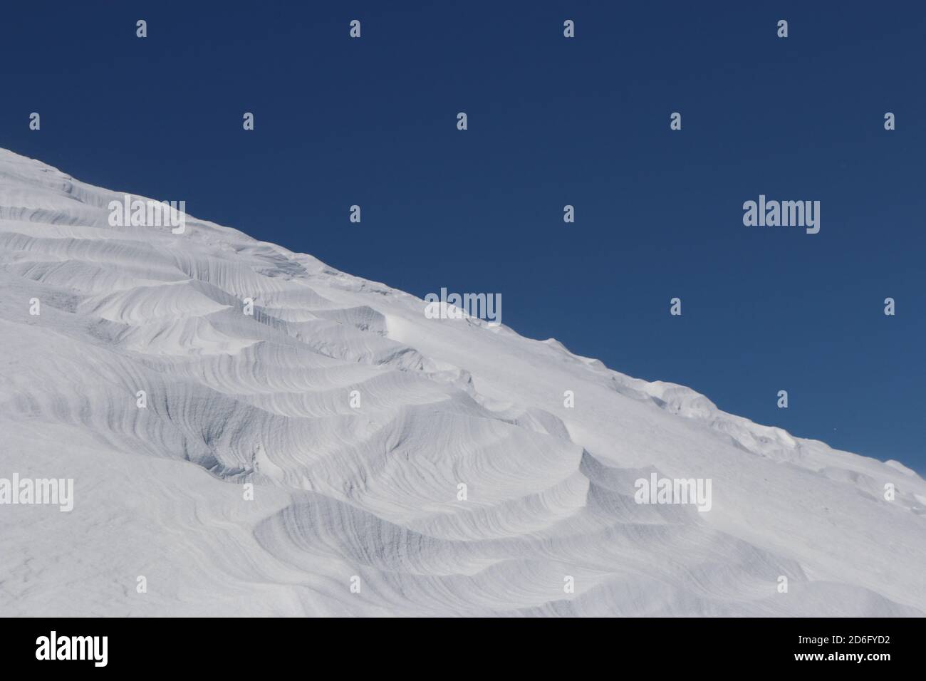 Patrones diagonales en la cresta de la nieve contra el cielo azul Foto de stock