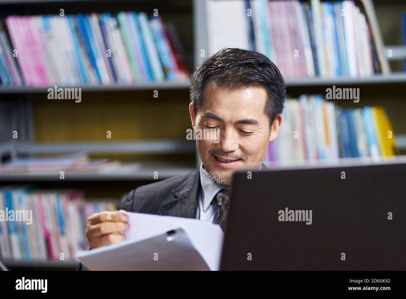 hombre de negocios asiático que trabaja en la oficina revisando un documento con satisfacción Foto de stock