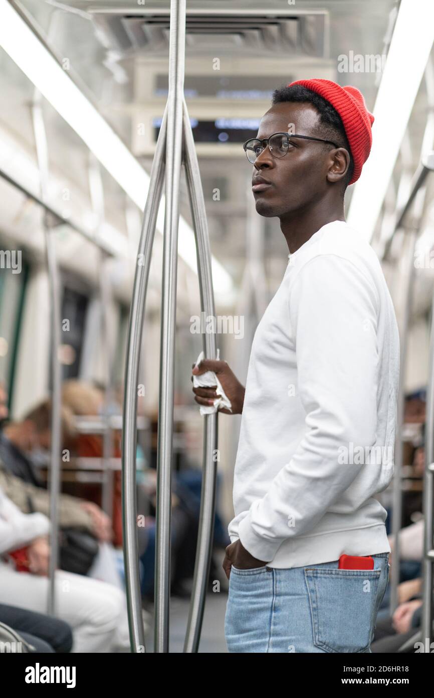 El hombre afroamericano en sombrero rojo no quiere llevar una máscara en el transporte público durante la pandemia de covid-19, niega la existencia de coronavirus, Foto de stock