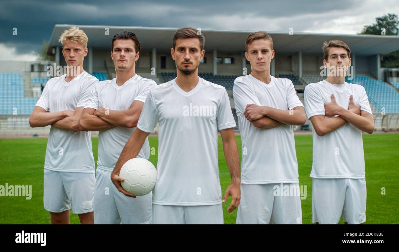 Equipo profesional de jugadores de fútbol posando para una foto de grupo de pie en un campo de fútbol. Foto de stock