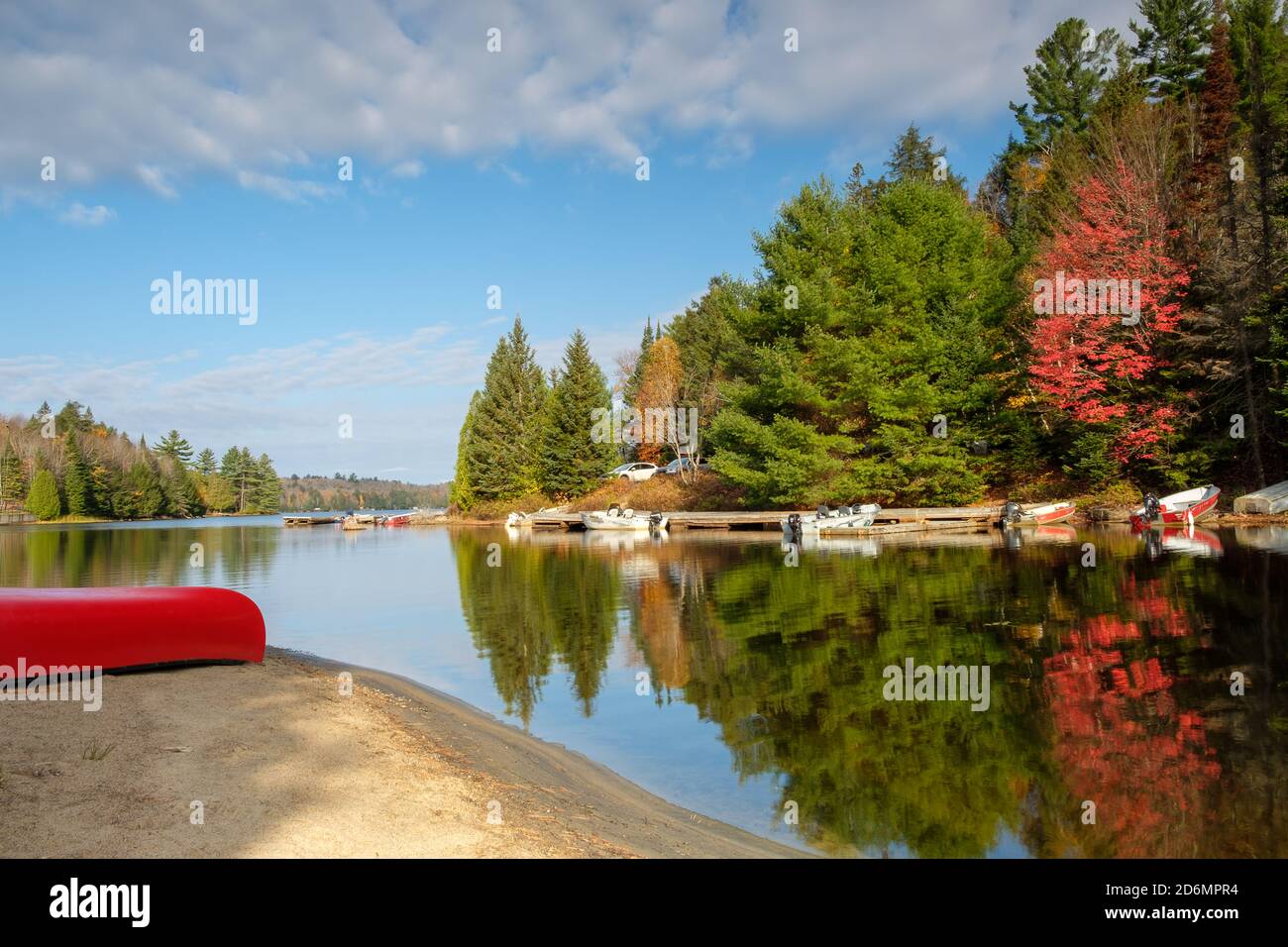Caída en Canadá - canoas rojas y árboles reflejados en un lago Foto de stock