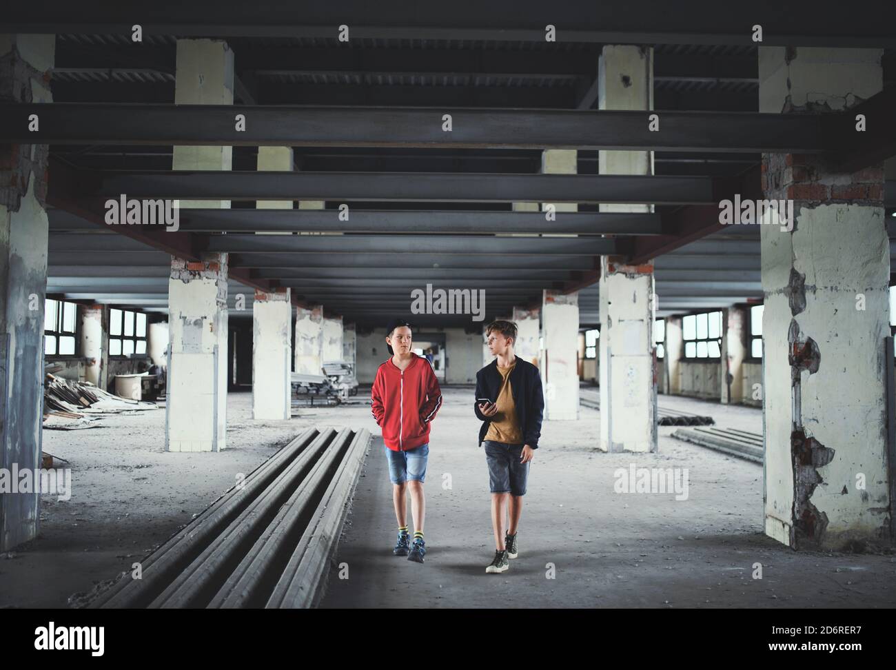 Adolescentes chicos se pandilla en el interior de un edificio abandonado, usando un smartphone. Foto de stock