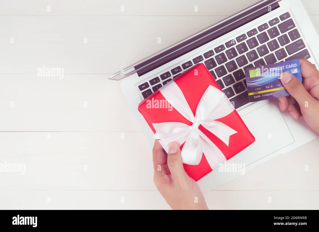 Mano de hombre con tarjeta de crédito y compras en línea para dar caja de  regalo con ordenador portátil sobre fondo de madera, presente para la  celebración en el escritorio Fotografía de