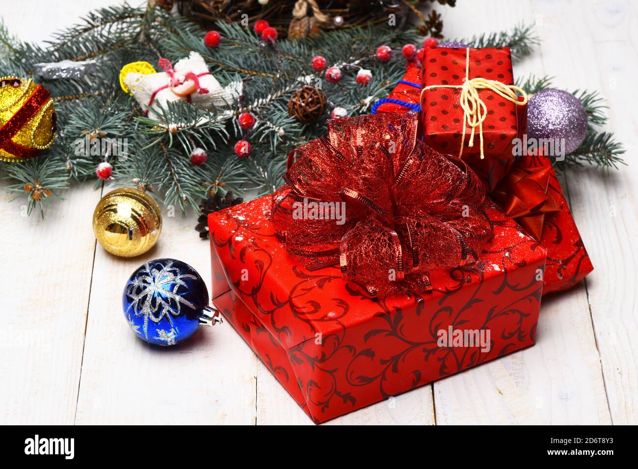 Adornos navideños sobre fondo blanco de textura de madera. Concepto de  tarjeta de invierno y año Nuevo. Composición de la decoración del árbol de  Navidad. Cajas con arcos rojos cerca de ramas
